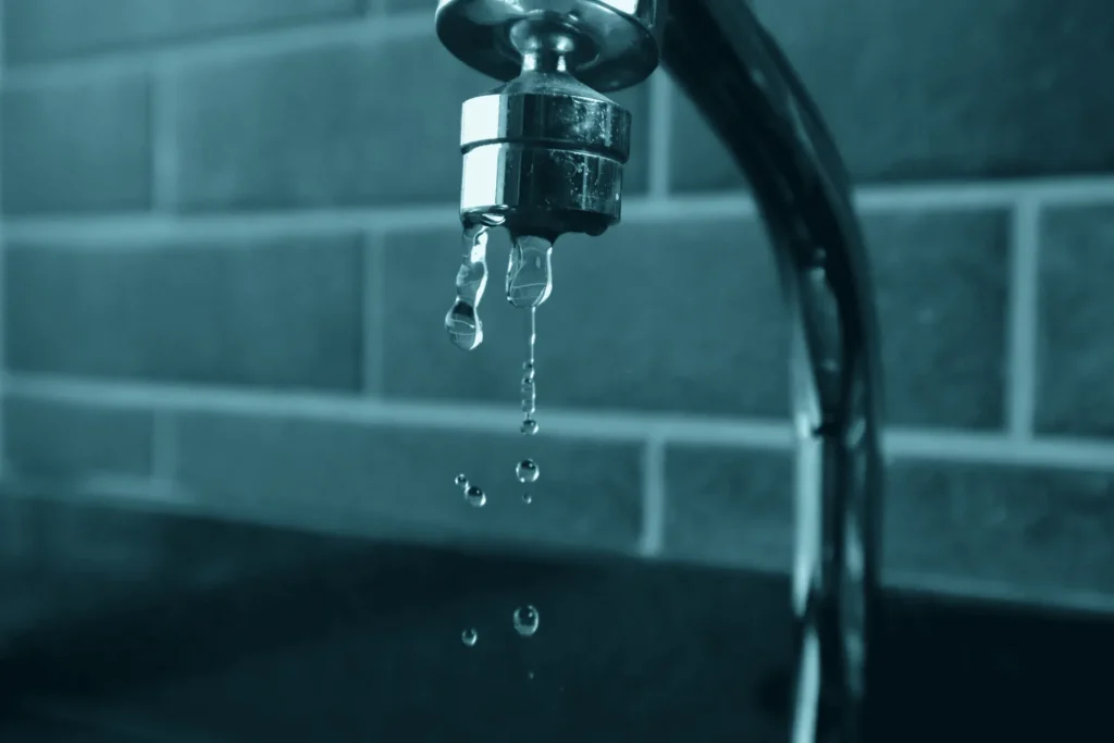 Waterdruppels uit een lekkende kraan voor een bakstenen muur